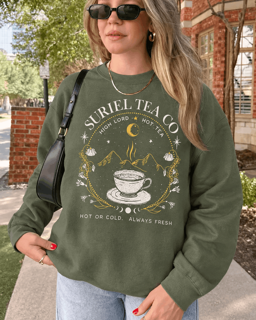 Bookish Closet Suriel Tea Co sweater shown in green, with a teacup, mountains, moon, stars and floral border